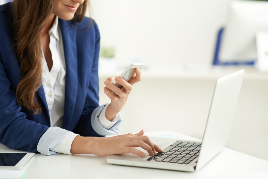 Teknoloji Bağımlılığı başlıklı yazı için bir elinde bilgisayar, diğerinde akıllı telefon olab bir iş kadını fotoğrafı