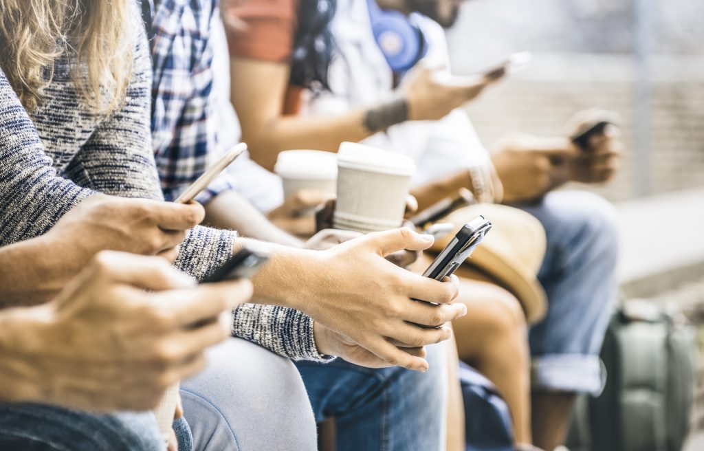 Teknoloji Bağımlılığı başlıklı yazı için ellerinde telefonla birarada oturan bir grup fotoğrafı
